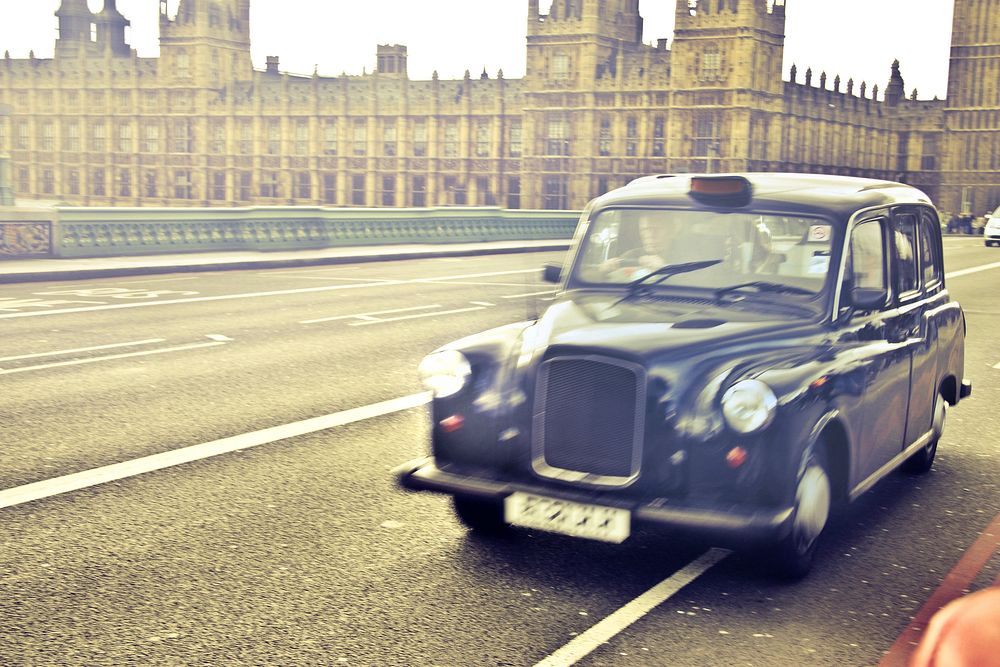 Free blue taxi cab in motion with Palace of Westminster in the background, London, England image, public domain CC0 photo. 