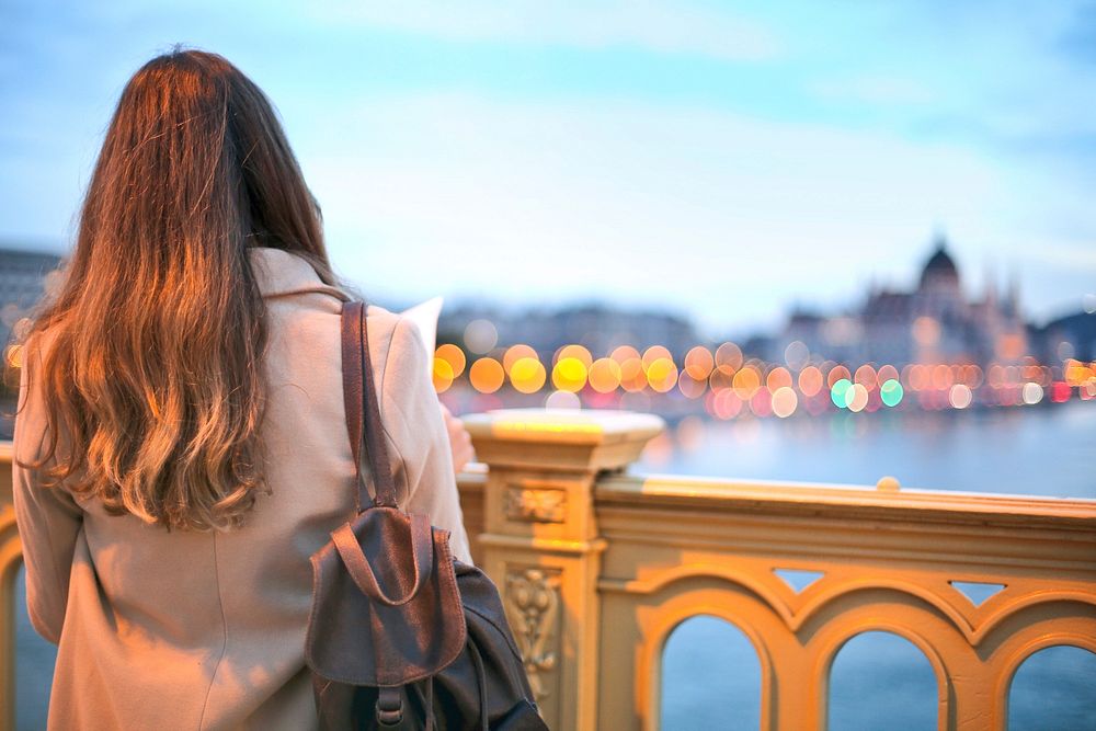 View From Behind, Young Woman In Trench Coat And Black Leather Backpack Looking Over Danube River