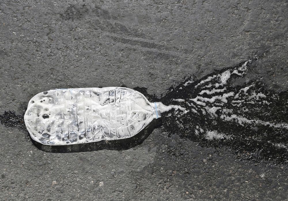 A crushed water bottle on the asphalt road