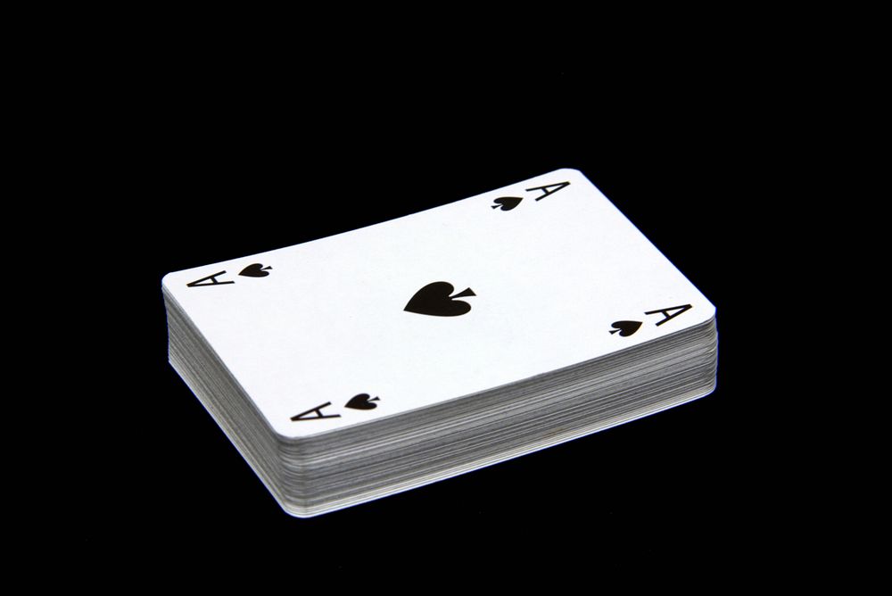 Stacked playing cards on black background. Free public domain CC0 image.