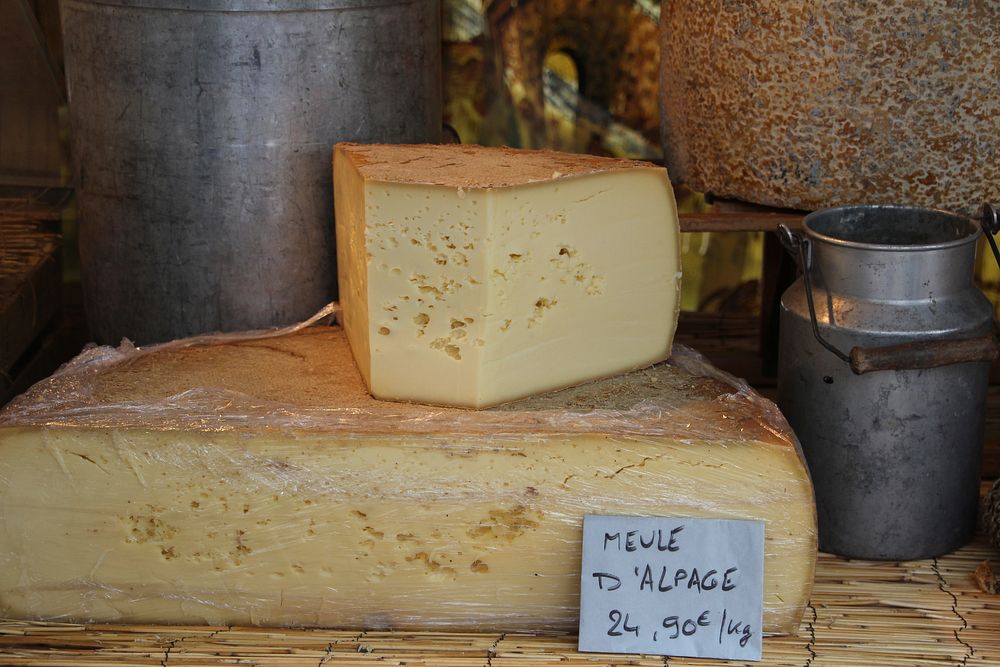 Stacked Gouda cheese on market counter.