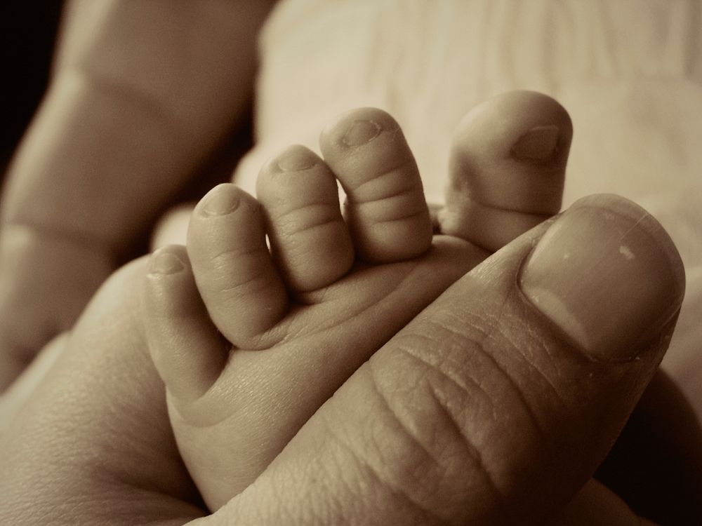 Father holding baby foot. Free public domain CC0 photo.