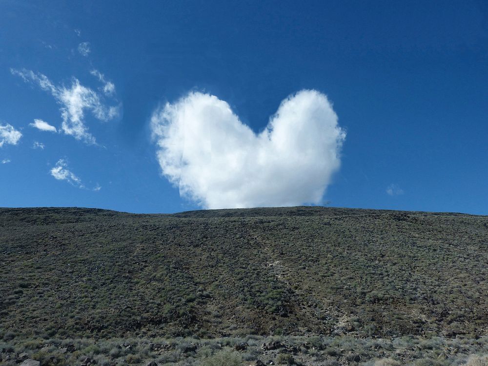 Heart-shaped cloud over a hill. Free public domain CC0 photo.