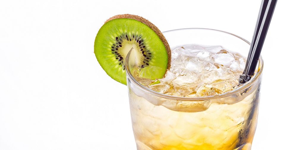 Close up of a glass of tropical cocktail garnished with a kiwi slice on white background