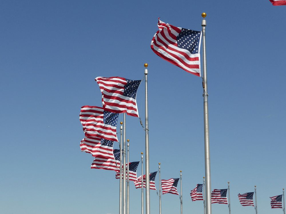 American flag waving against blue sky. Free public domain CC0 photo.
