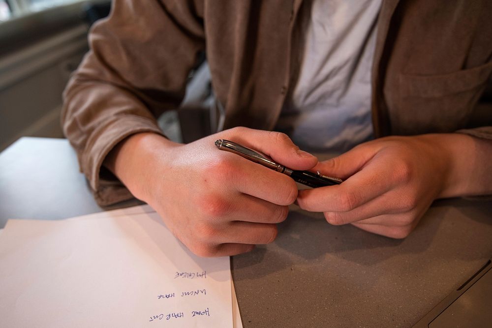 Close up of young man hands with pen, taking notes on paper