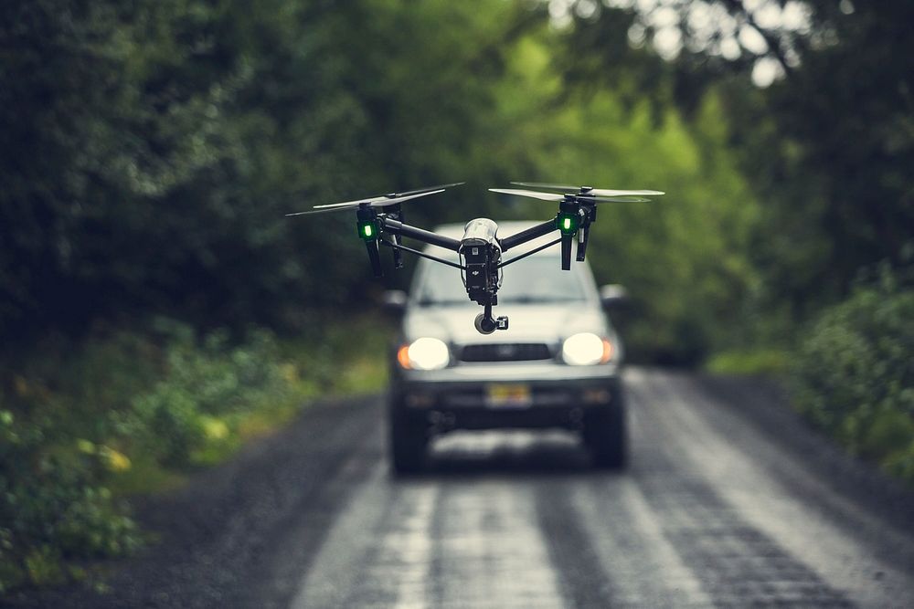 Free quad copter drone flying over the road with a car in the background image, public domain CC0 photo.