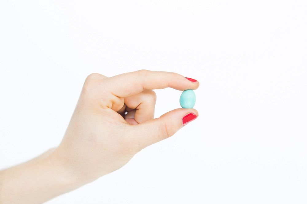 A woman holds a single chocolate mini egg in her hand