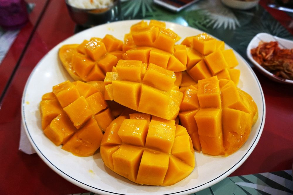 Slice of mangoes serve on white plate. Free public domain CC0 photo.