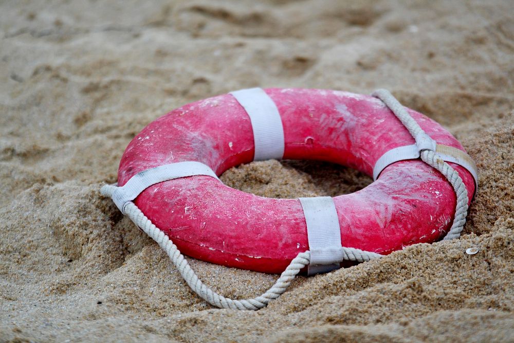 Life buoy on beach sand. Free public domain CC0 image.