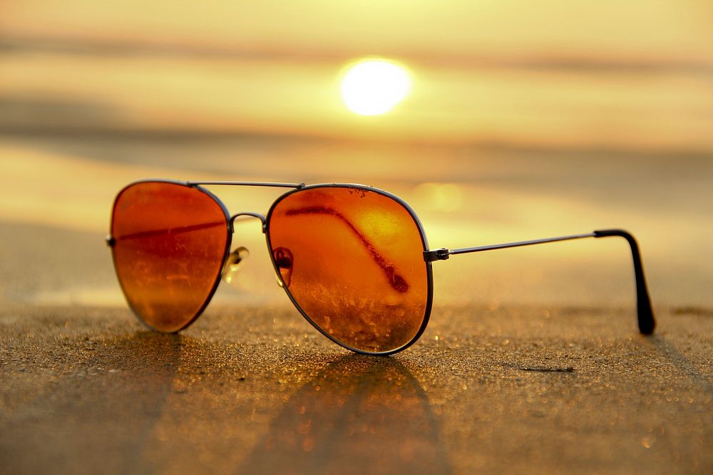 Sunglasses on beach sand at sunset. Free public domain CC0 image.