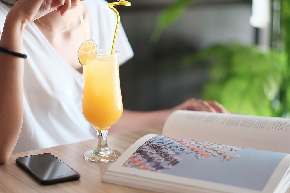 Free woman with summer drink reading a book photo, public domain CC0 image.