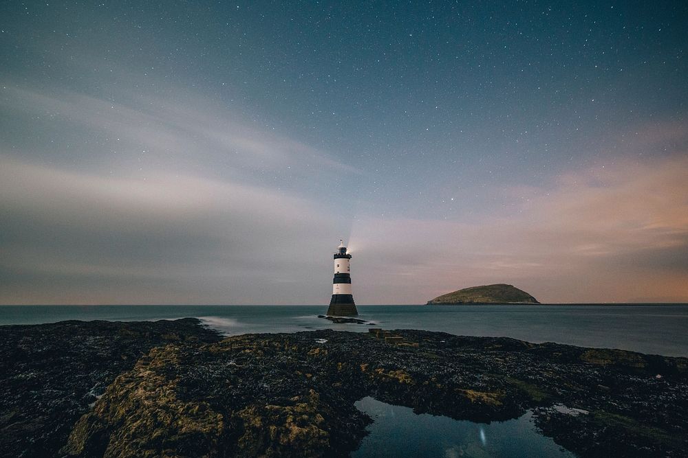 Lighthouse by the sea under starry sky, free public domain CC0 photo.