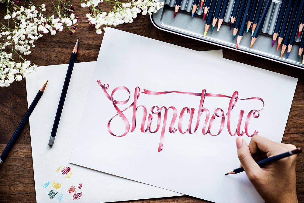 Female artist writing the word 'shopoholic' on a paper