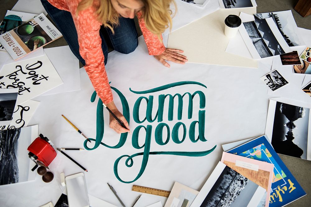 A female artist writing the word 'damn good' on a paper