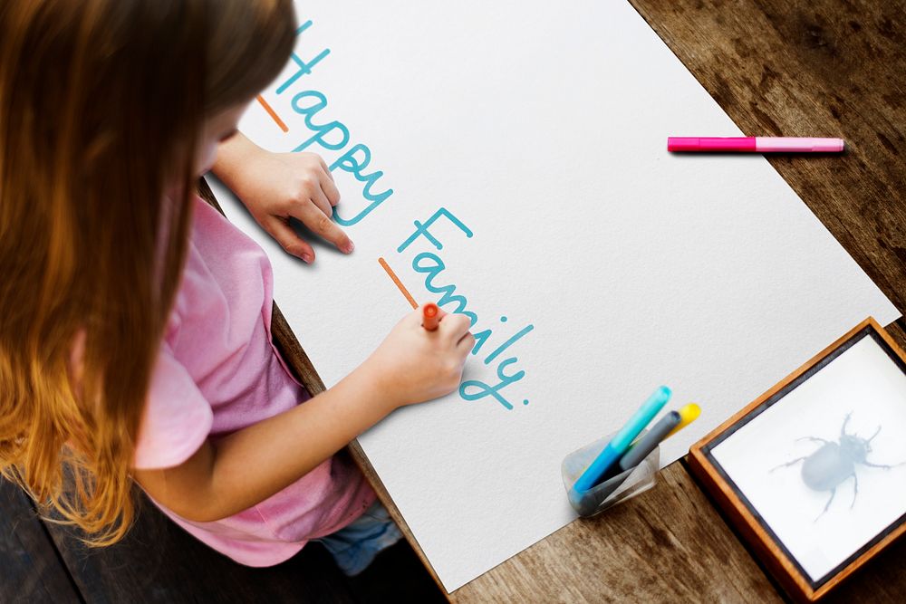 Kid writing a phrase Happy Family on a paper