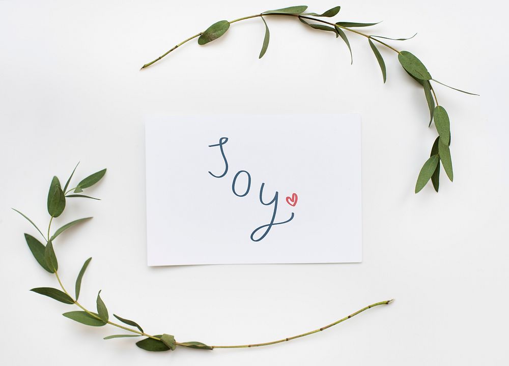 Card with a text Joy in a green plant decoration