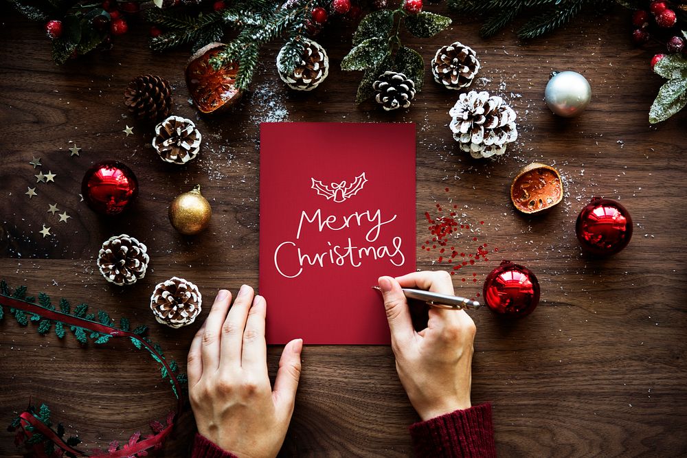 Woman writing Merry Christmas on a card