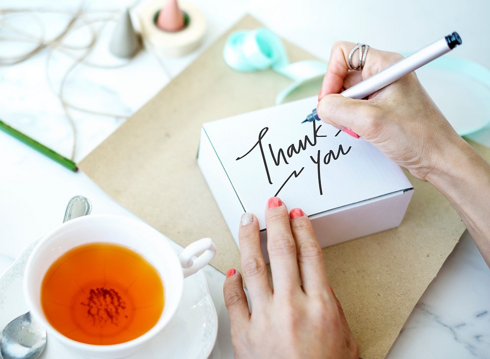 Woman writing Thank You on a white box