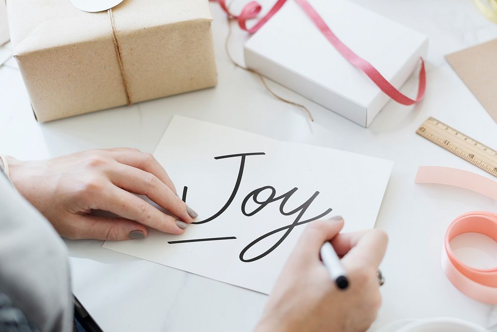 Woman writing a text Joy on a card