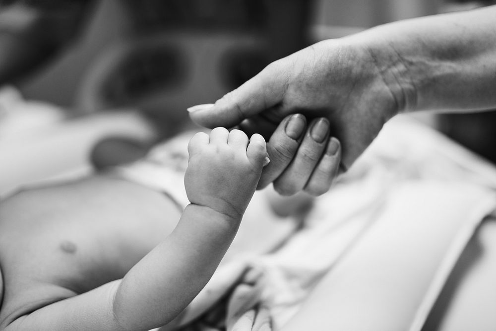 Newborn baby holding mother's hand with love