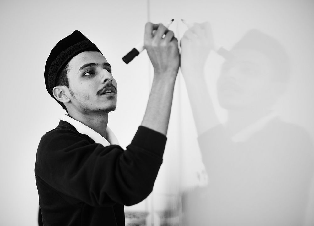 Young muslim man is writing on a white board