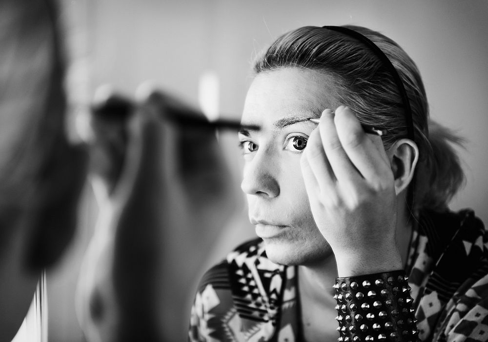 Drag queen applying makeup in a mirror