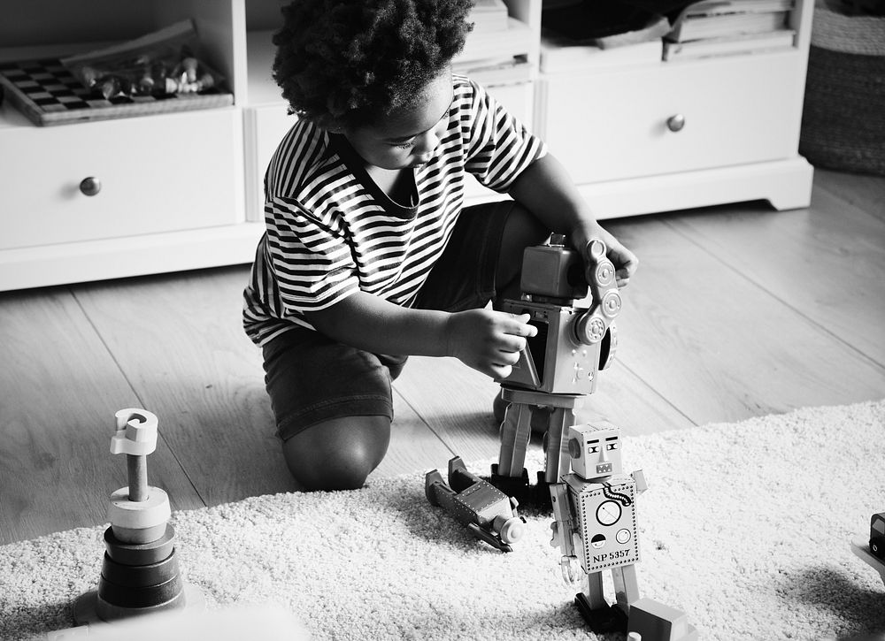 African boy playing with a robot at home