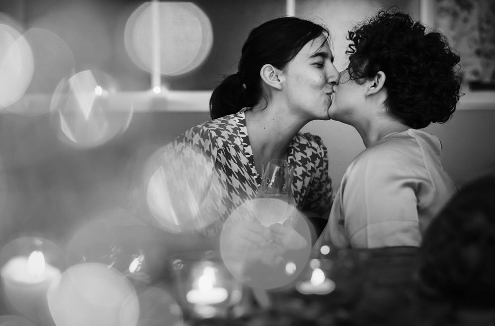 Lesbian couple kissing during dinner