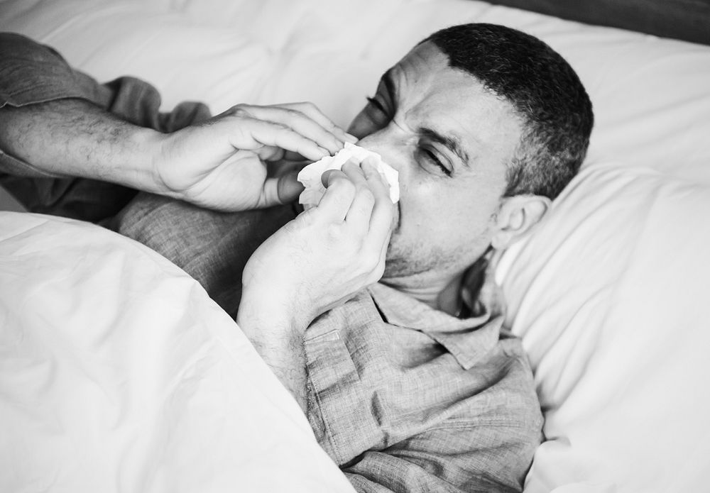 Sick man sneezing in bed