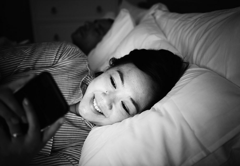 Asian woman using phone on a bed