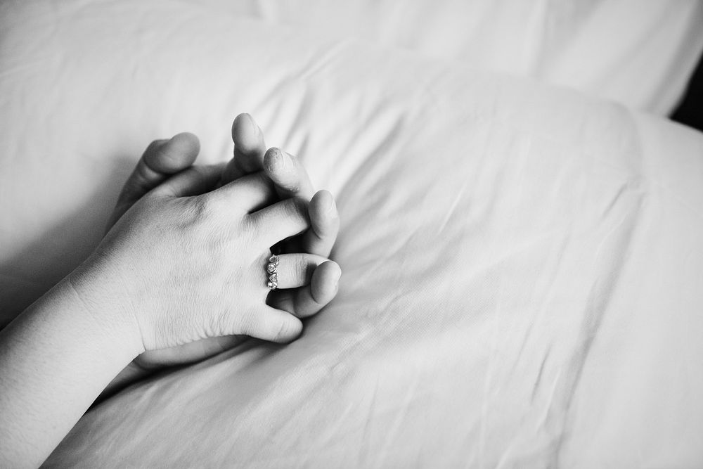 Couple holding hands on the bed