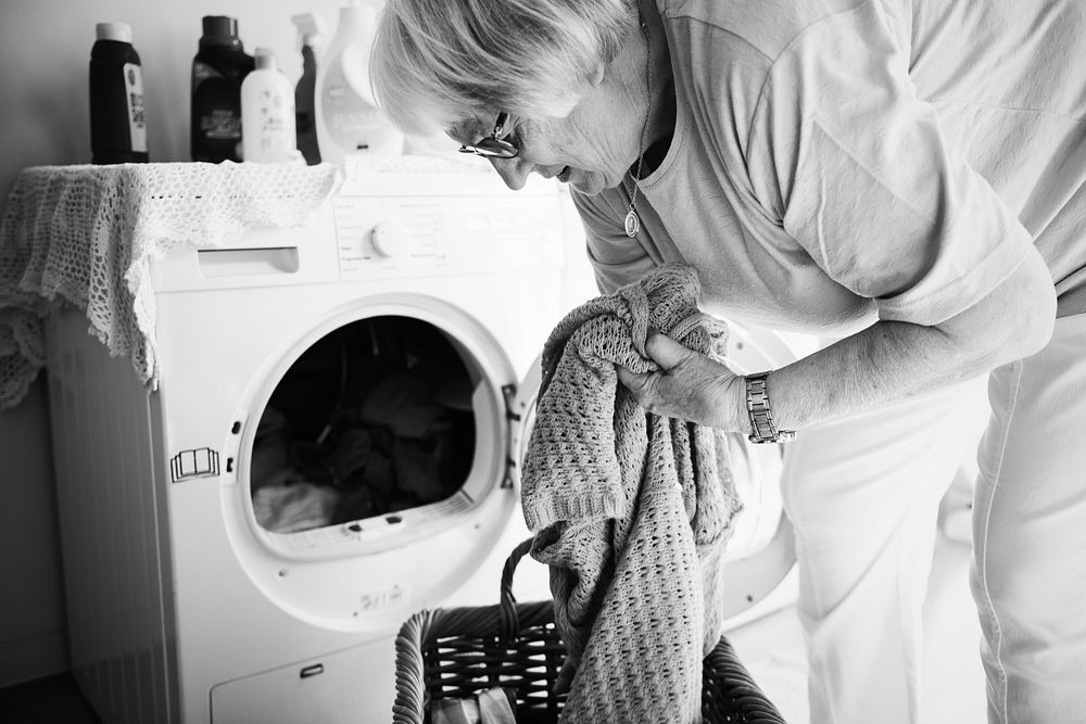 Elderly woman doing laundry at home