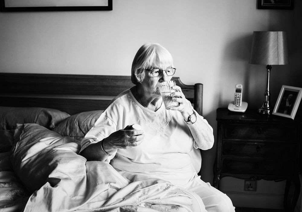 Senior woman taking medicine in bed