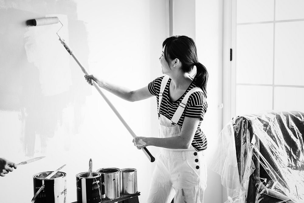 Asian woman painting the house wall