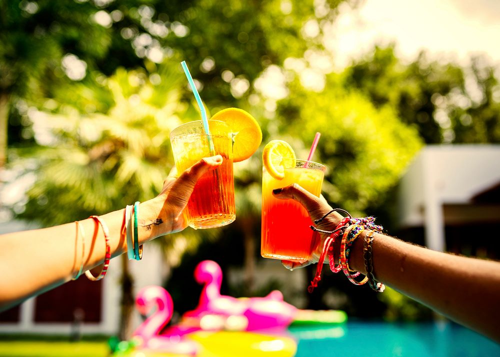 Friends drinking colorful driks at a pool party