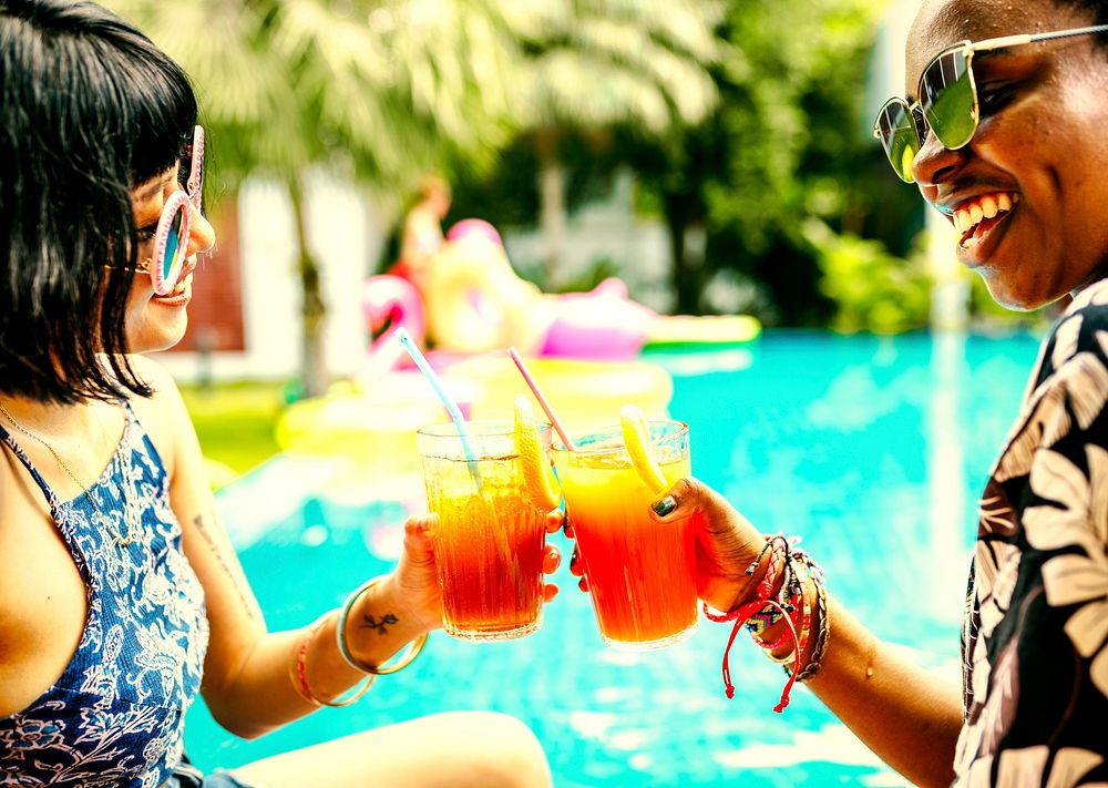 Friends drinking colorful drinks at a pool party