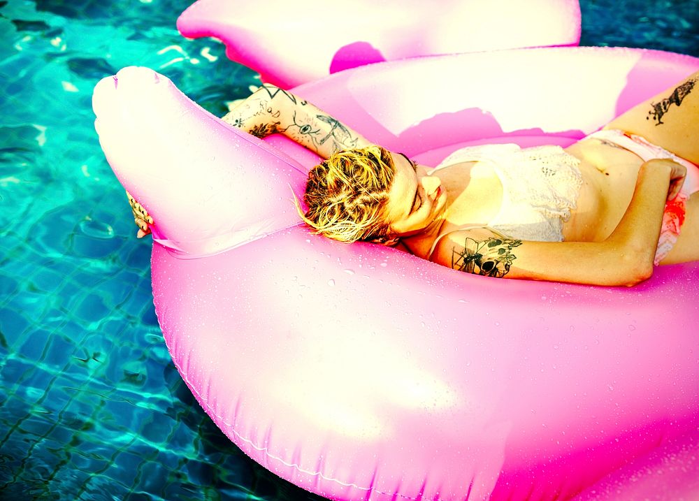 Tattooed girl floating around in a pool