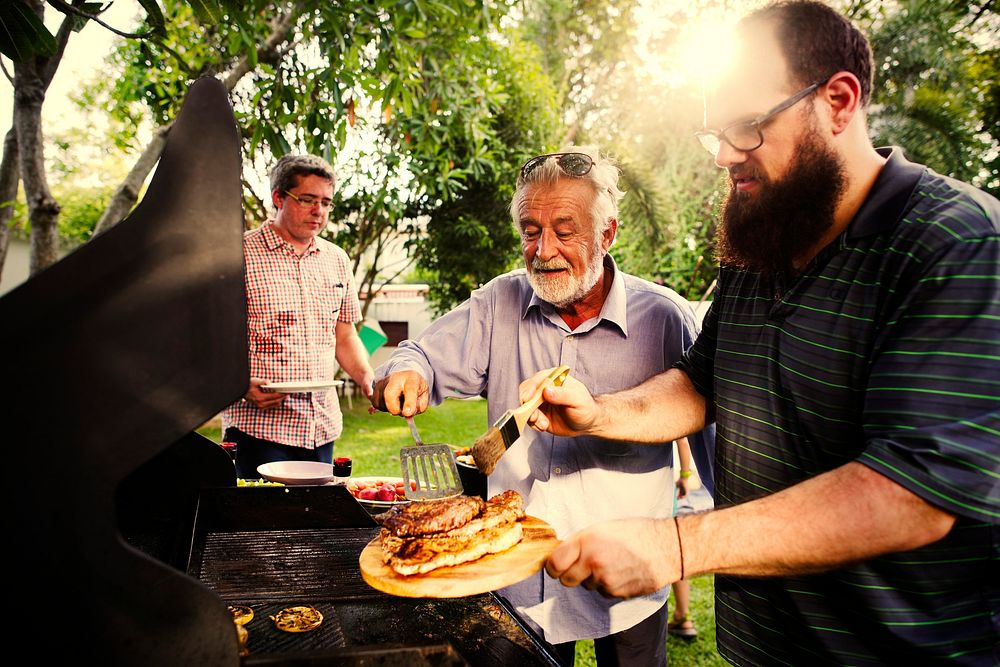 Men barbecuing meat at a summer party