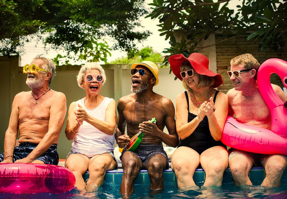 Cool seniors acting youtful by a swimming pool