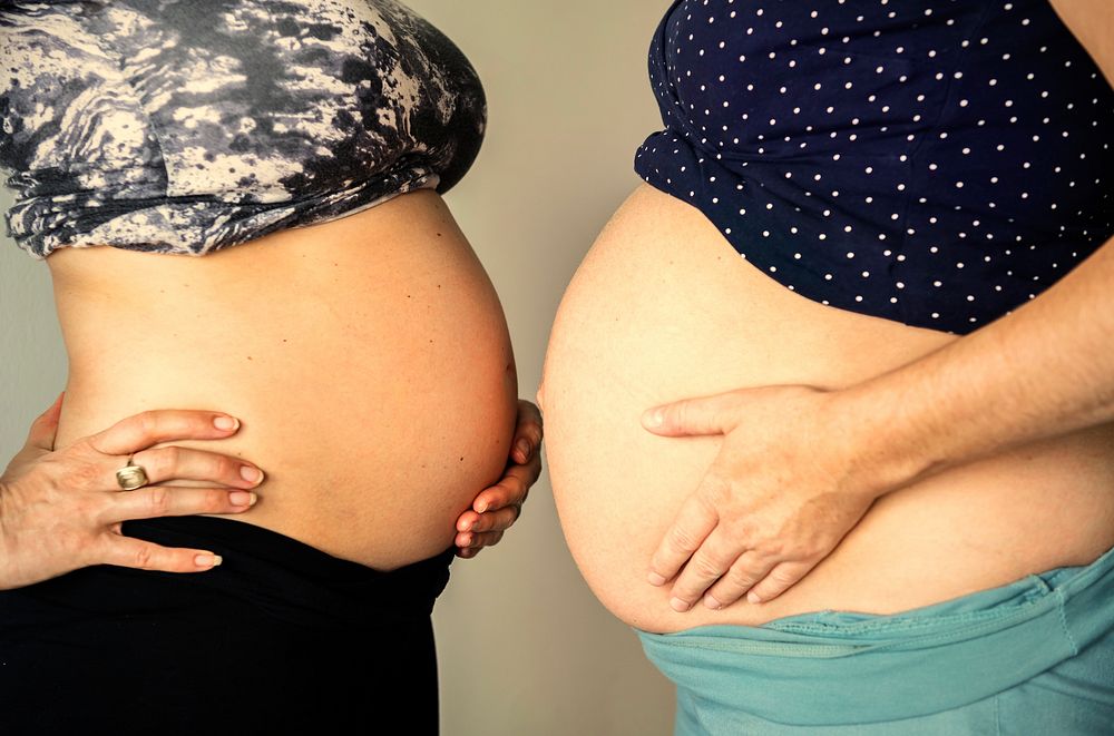 Pregnant women comparing baby bumps