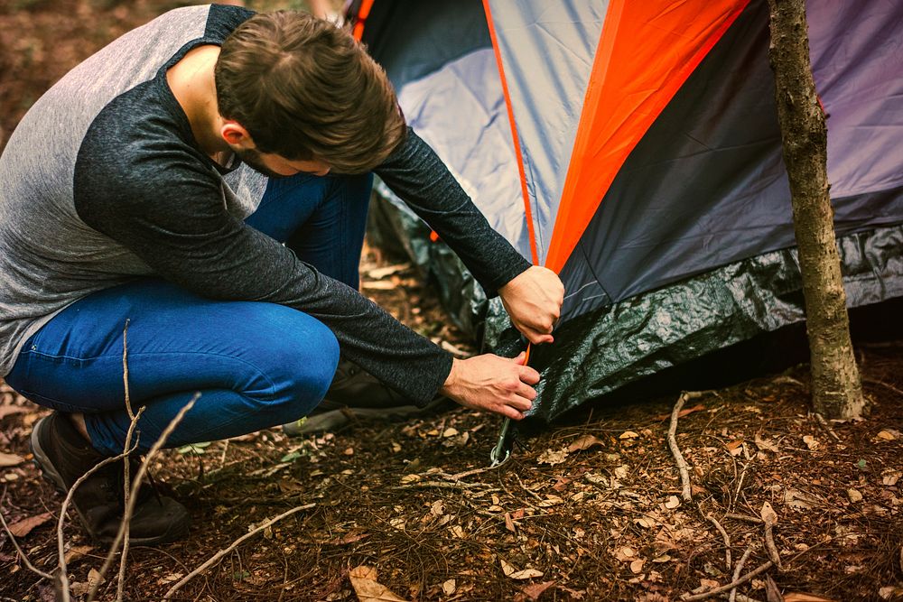 Man putting up a tent in the forest