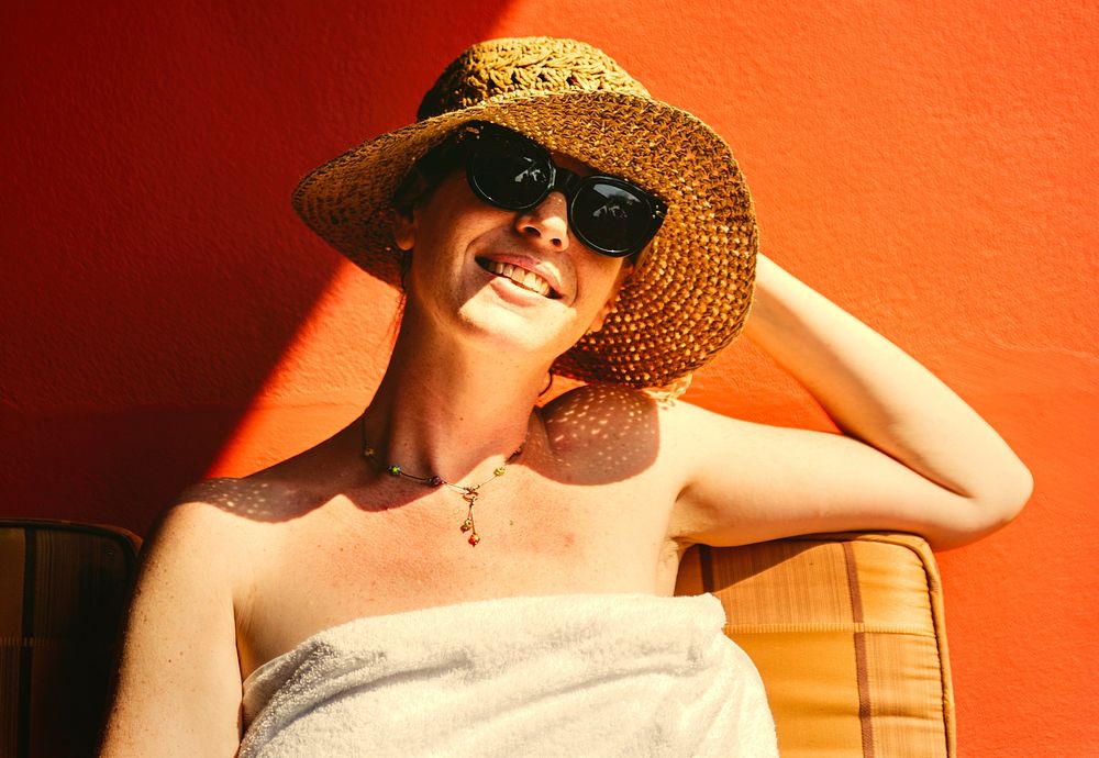 Caucasian woman sunbathing by an orange wall
