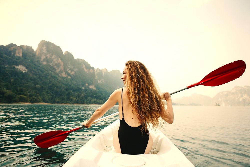 Woman paddling a canoe through a national | Premium Photo - rawpixel