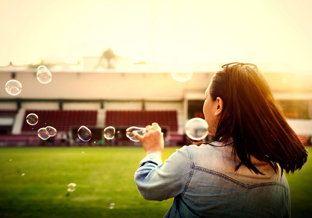 Woman blowing bubbles at a field