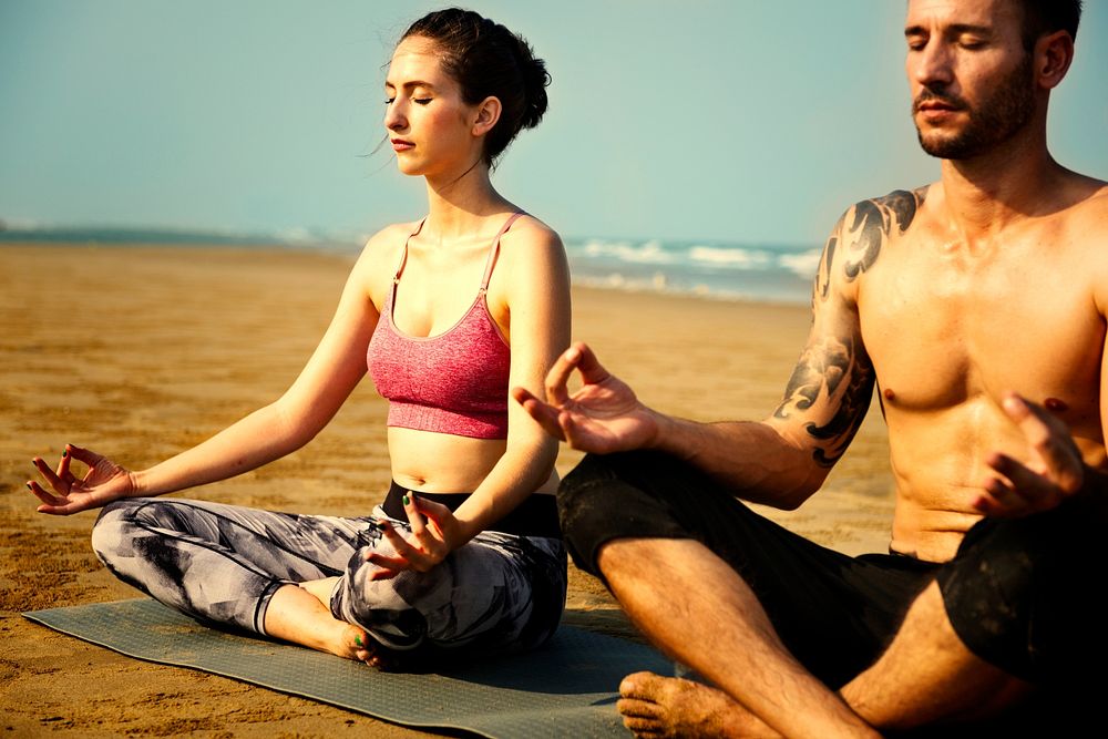 Couple practicing yoga at the beach