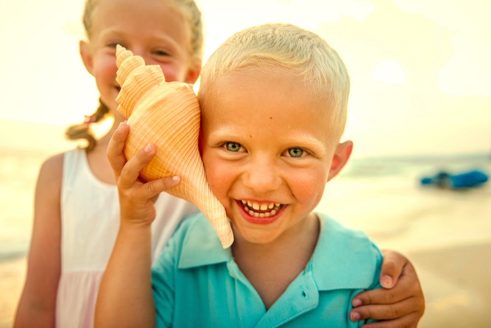 Blond boy listening to the waves in a seashell