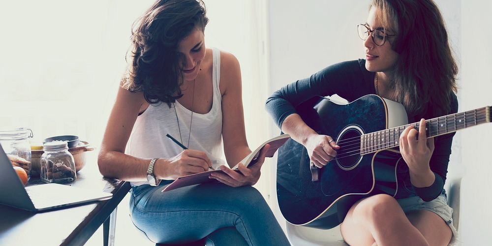Lesbian couple playing guitar in their home