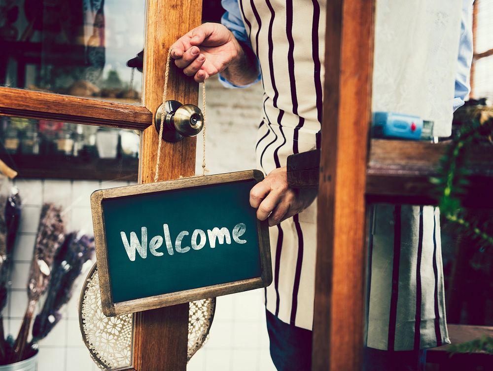 Welcome sign hanging on a glass door