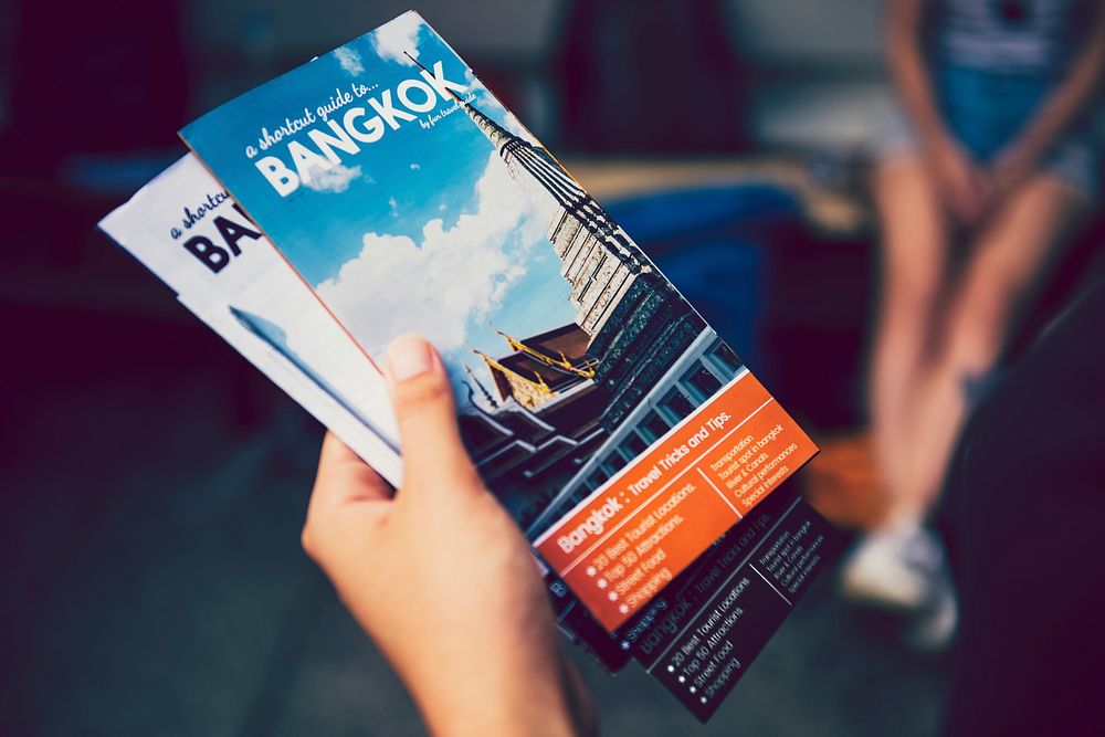 Tourist holding Bangkok travel guide brochures